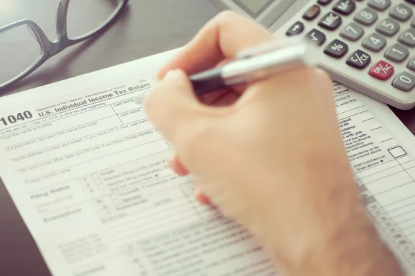 Człowiek, wypełniając formularz indywidualnego podatku dochodowego — Zdjęcie stockowe