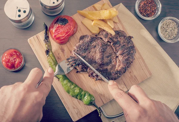 Homme coupant et mangeant un steak de bœuf grillé — Photo