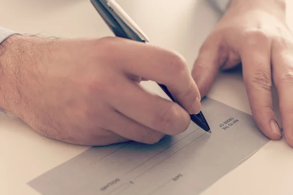 Geschäftsmann schreibt einen Zahlungsscheck — Stockfoto