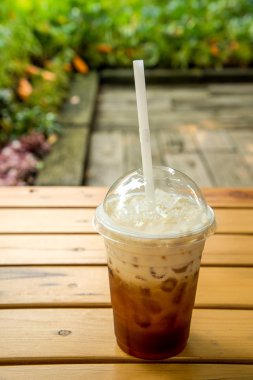 Süt çay, buzlu çay, ahşap masa üzerinde plastik cam.