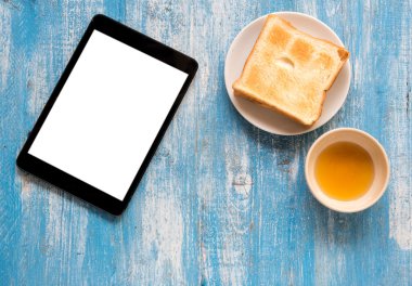 Beyaz ekran Tablet, tost, tatlım mavi ahşap zemin üzerinde.