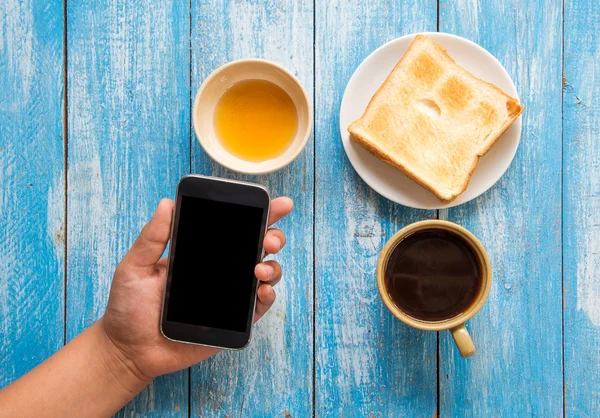 Black display Smart phone in hand , Toast , Honey , Coffee cup o