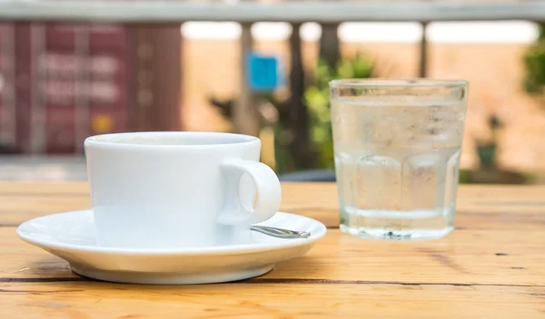 Weiße Kaffeetasse, Glaswasser auf Holzboden. — Stockfoto