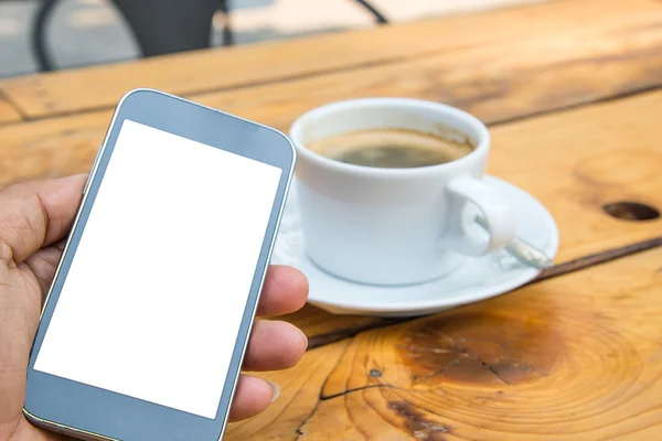 Vit skärm smart telefon i handen, vit kaffekopp på trä flo — Stockfoto