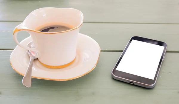 Svart skärm smart phone, vit kaffekopp på trägolv. — Stockfoto