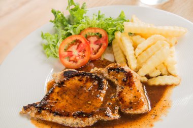 Beyaz tabak, bardak su, patates kızartması ahşap üzerinde domuz eti biftek 