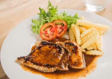 Beyaz tabak, bardak su, patates kızartması ahşap üzerinde domuz eti biftek 