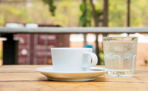 Weiße Kaffeetasse, Glaswasser auf Holzboden. — Stockfoto