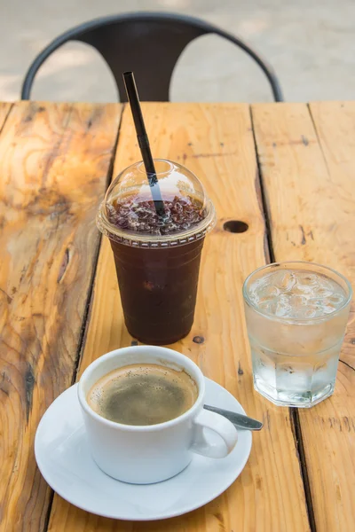 Eiskaffee in Kunststoffglas, Kaffeetasse, Glaswasser auf Holz — Stockfoto