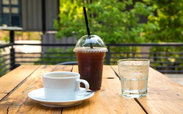 Eiskaffee in Kunststoffglas, Kaffeetasse, Glaswasser auf Holz — Stockfoto