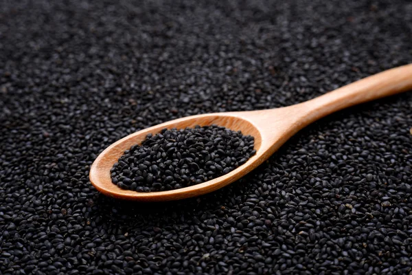 Sésamo negro en cuchara de madera sobre fondo de sésamo . — Foto de Stock