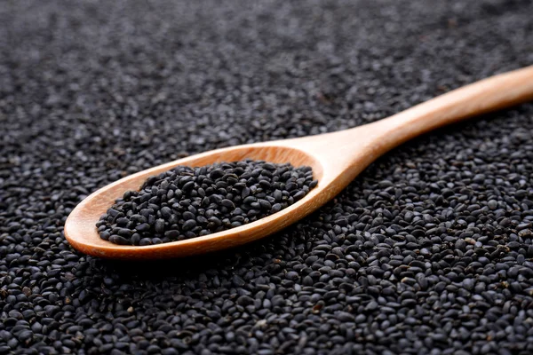 Sésamo negro en cuchara de madera sobre fondo de sésamo . — Foto de Stock