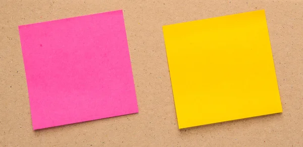 Geel, roze papier etiketten plein op bruin karton. — Stockfoto