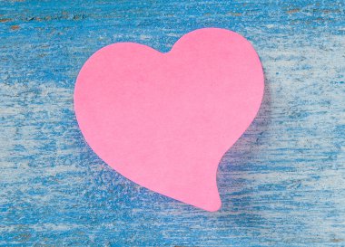 Pembe etiket kağıt kalp mavi ahşap zemin üzerinde.
