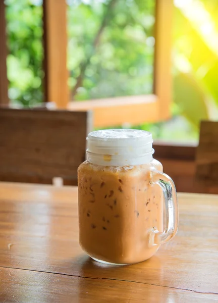 Milchtee mit Eis im Glasgriff auf Holztisch. — Stockfoto