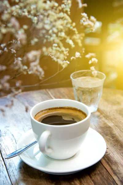 Tazza di caffè bianco con fiore secco sul tavolo di legno . — Foto Stock
