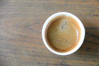 Ahşap masa üzerinde beyaz kağıt bardak kahve.