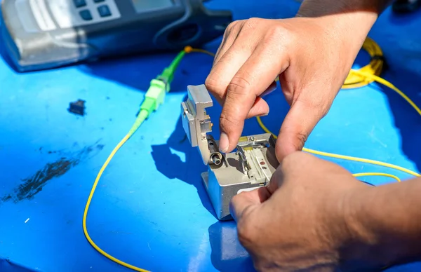 Технік, використовуючи розсіювач різання оптичного волокна на синьому столі з — стокове фото