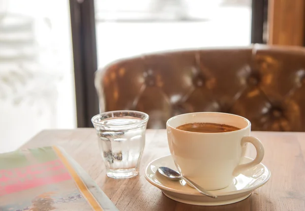 Чашка белого кофе, Газета и стеклянная вода на деревянном столе . — стоковое фото