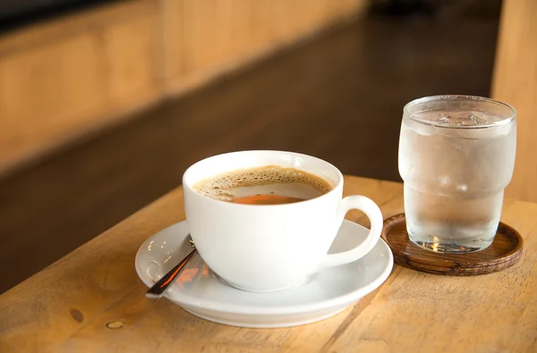 나무 테이블에 흰색 컵과 유리 물에 커피. — 스톡 사진