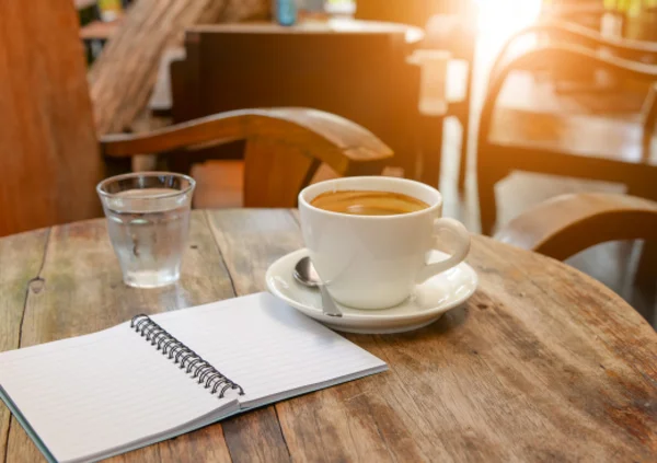 Kawa z notebooka i szkło wodne na drewnianym stole. — Zdjęcie stockowe