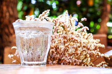 Kuru çiçek arka plan ile ahşap masa cam su. Odaklanmak 