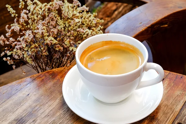 Bílá káva pohár s suché květiny na dřevěný stůl. Zaměření káva. — Stock fotografie