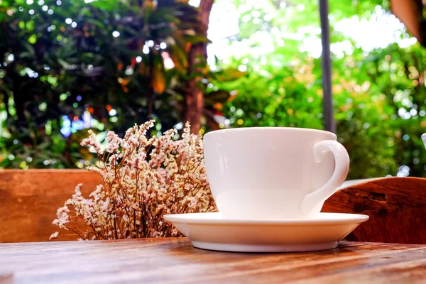 Чашка белого кофе с сухим цветком на деревянной столе.Фокус кофе . — стоковое фото