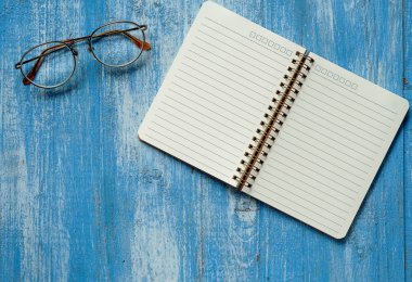 Gözlüklü mavi ahşap zemin üzerinde beyaz dizüstü bilgisayar.