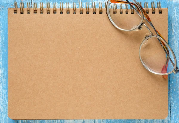 Brown notebook with glasses on blue wooden floor. — Stock Photo, Image
