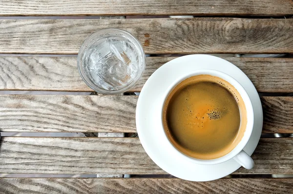 Tasse à café blanche et eau en verre sur table en bois . — Photo