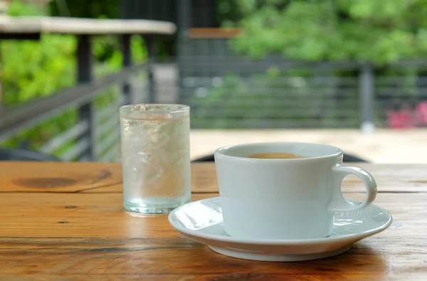 White coffee and glass water on wooden table.blurred green backg