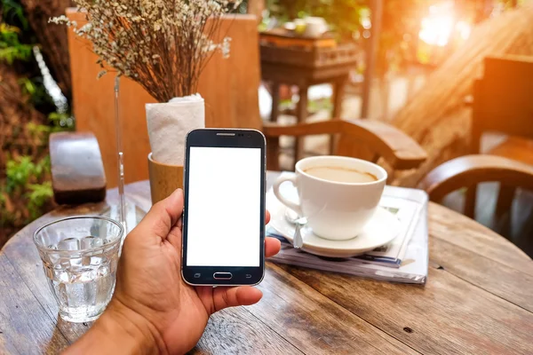 Smart telefon i handen med kaffe suddig bakgrund. — Stockfoto