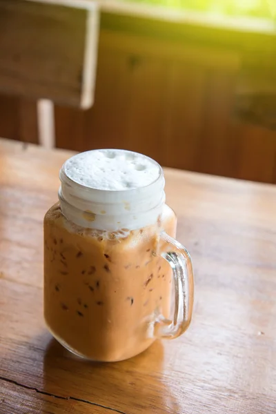 Milchtee mit Eis im Glasgriff auf Holztisch. — Stockfoto