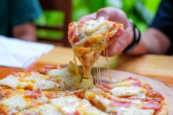 Menino preso por pizza havaiana em placa de madeira . — Fotografia de Stock