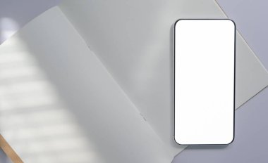 Beyaz kitap kağıdına yerleştirilmiş akıllı telefonun yakın plan görüntüsü, iletişim konsepti.