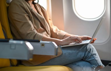 Uçak yolculuğu sırasında dizüstü bilgisayar kullanan bir kadın..