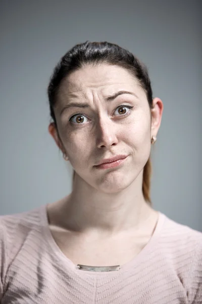 Frau blickt flehend über grauen Hintergrund — Stockfoto