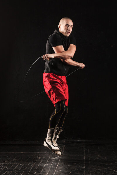 Ноги мускулистого человека с скакалкой
