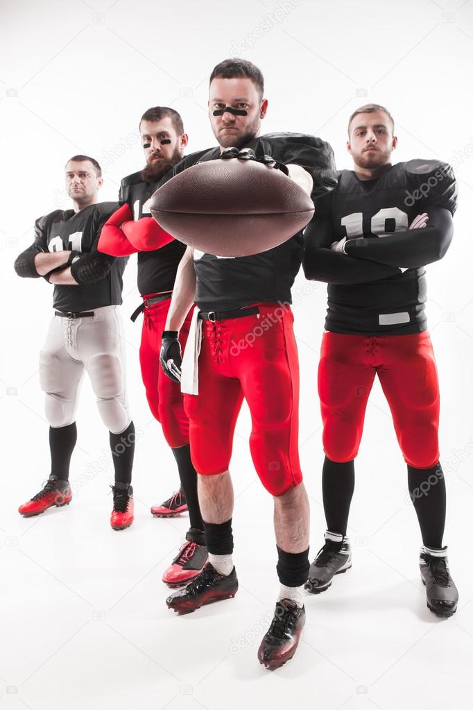 The four american football players posing with ball on white background