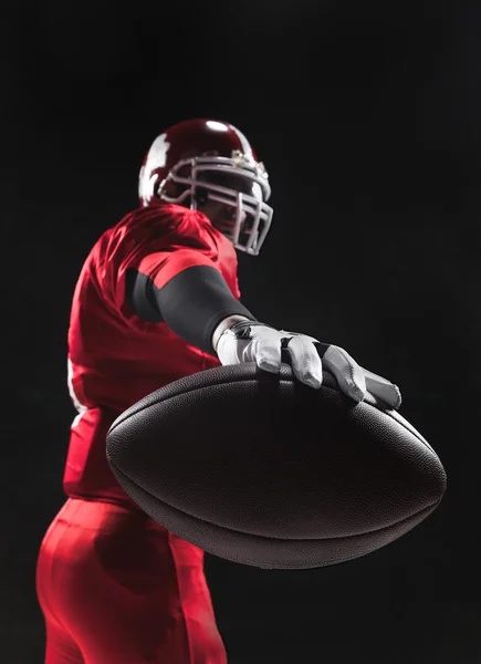 American Football-Spieler posiert mit Ball auf schwarzem Hintergrund — Stockfoto
