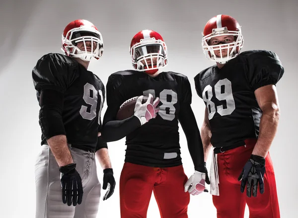 De drie Amerikaanse voetballers poseren met bal op witte achtergrond — Stockfoto