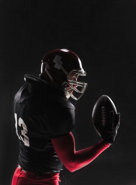 Siyah arka plan üzerinde topu ile poz Amerikan futbolu oyuncusu