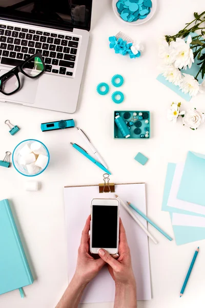 Les mains féminines et le téléphone intelligent contre les objets bleus sur blanc — Photo