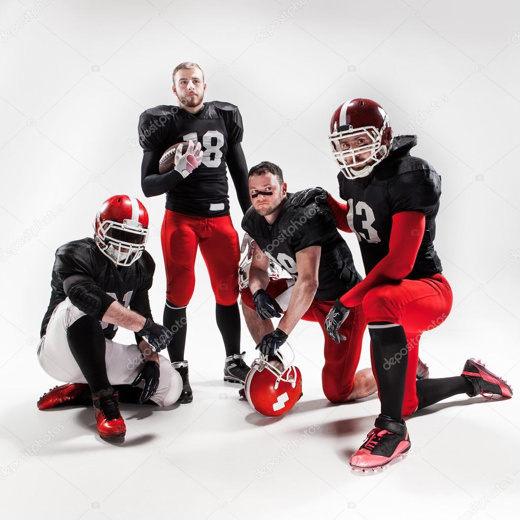 The four american football players posing with ball on white background