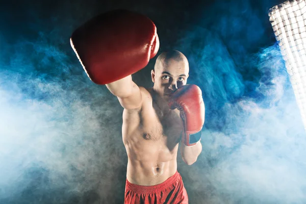 Der junge Mann kickboxt in blauem Rauch — Stockfoto