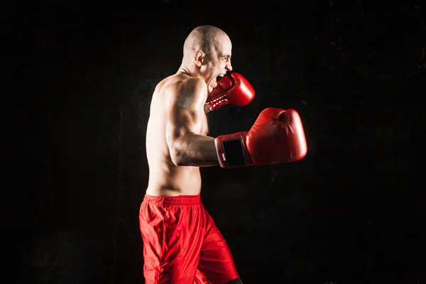 The young man kickboxing on black — Stock Photo, Image