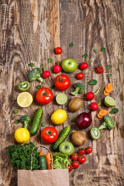 Grönsaker från en papperspåse på träbord — Stockfoto