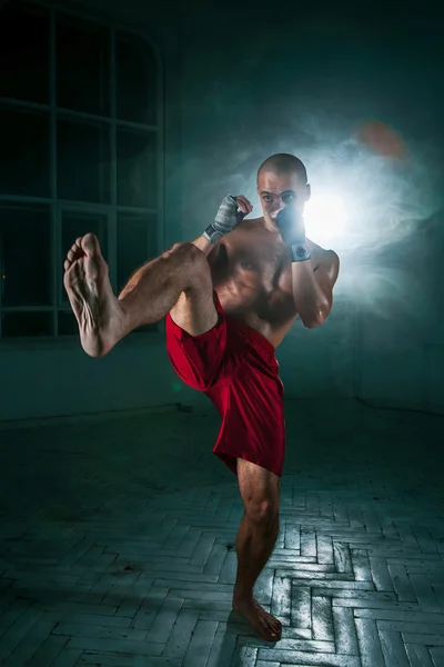 Der junge Mann kickboxt in blauem Rauch — Stockfoto