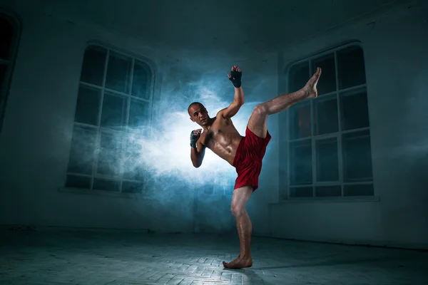 The young man kickboxing in blue smoke — Stock Photo, Image